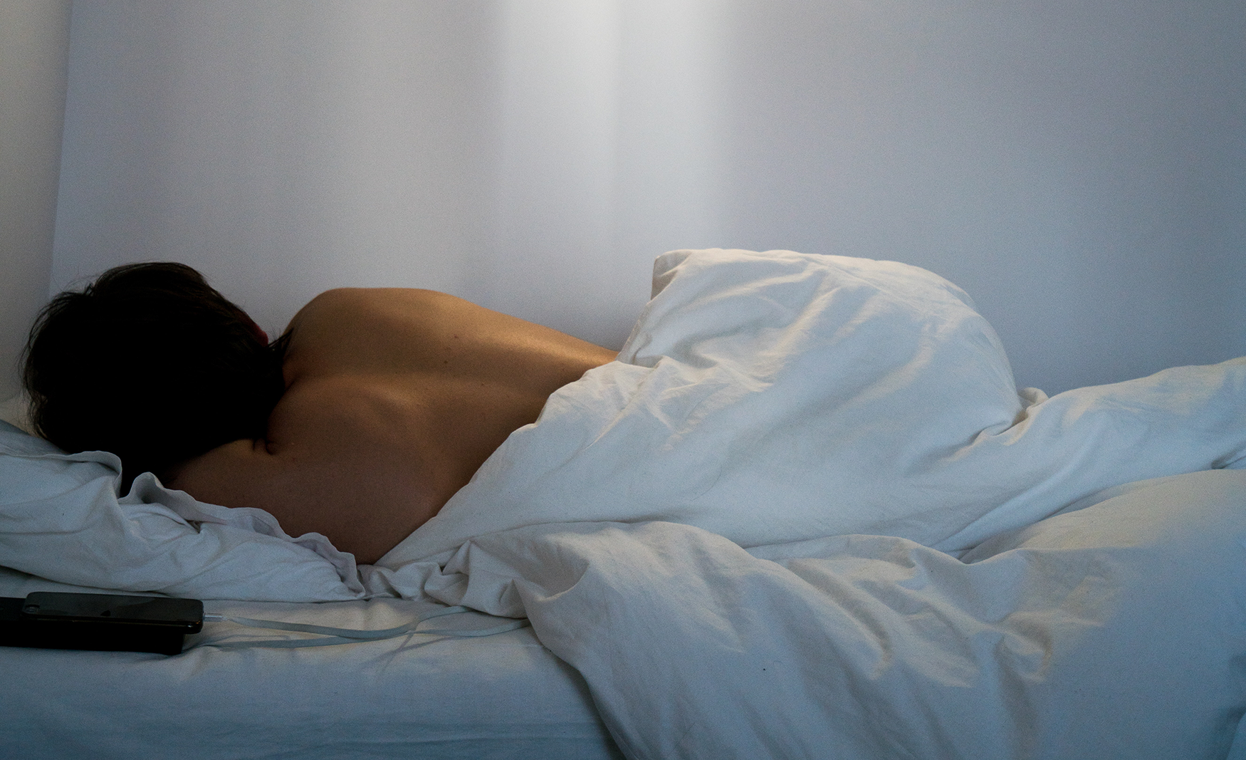 woman sleeping in white bed facing away