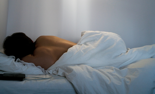 woman sleeping in white bed facing away