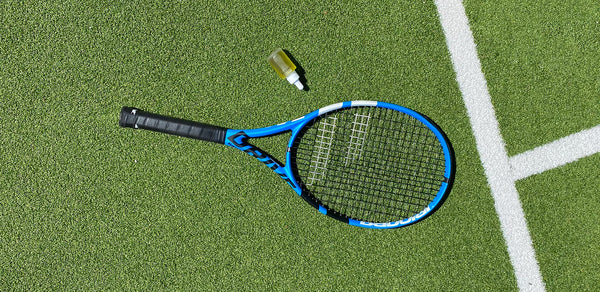CBD oil bottle and tennis racket on court 