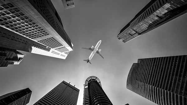 black and white plane flying over city