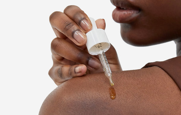 woman's shoulder with cbd oil pipette and cbd oil on skin