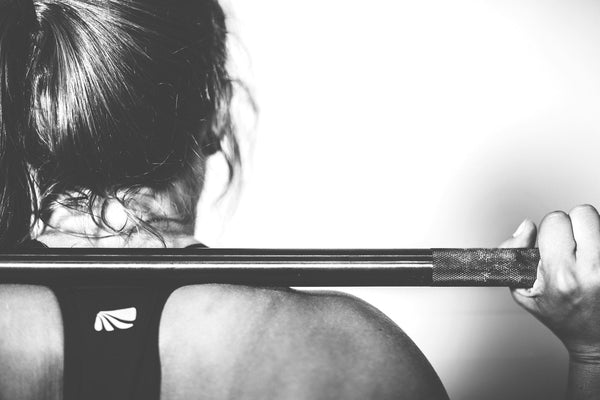 woman lifting barbell on shoulders